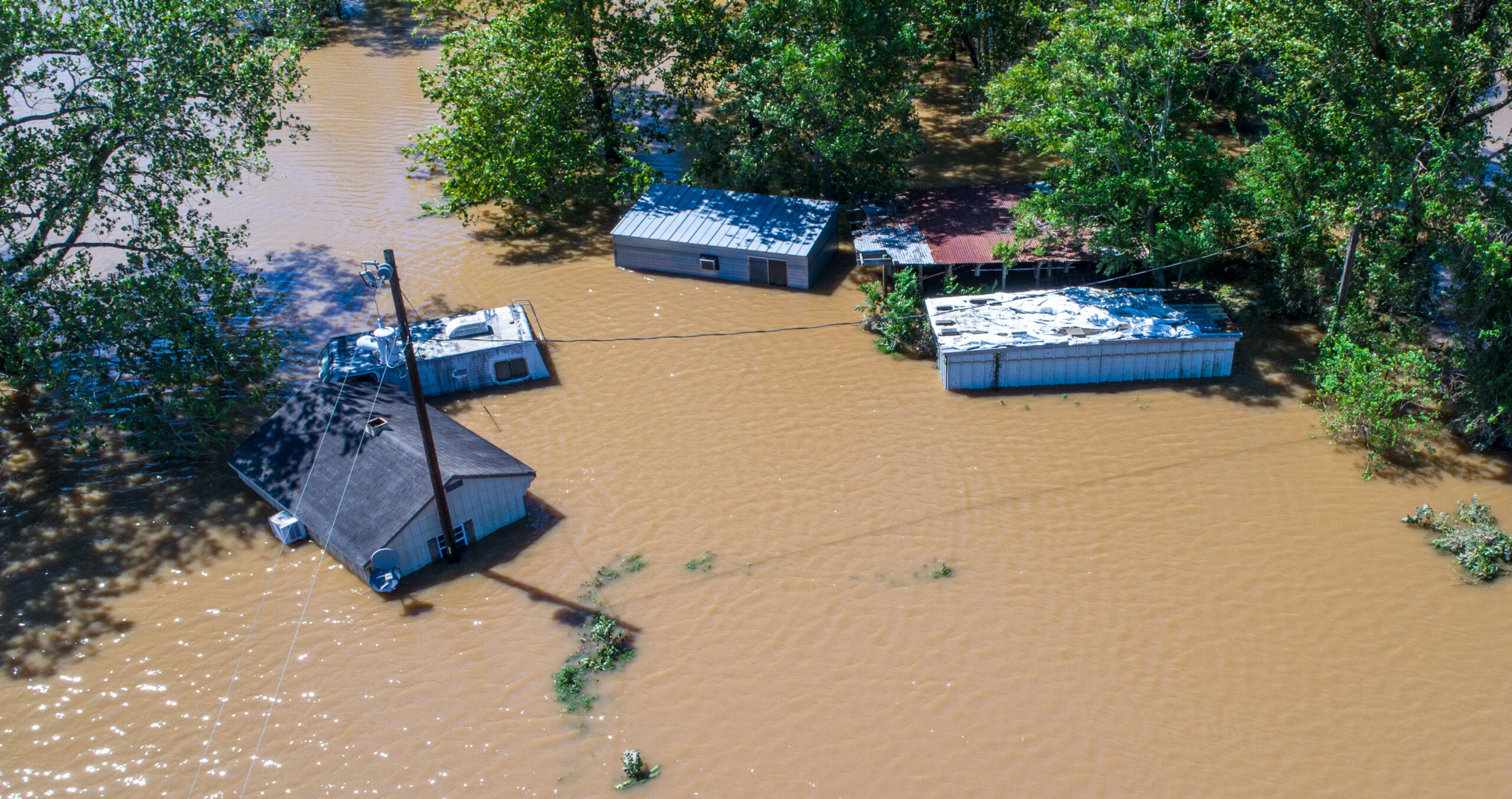 Five small trailer homes are surrounded by - and partially submerged in - floodwaters in this aerial view image