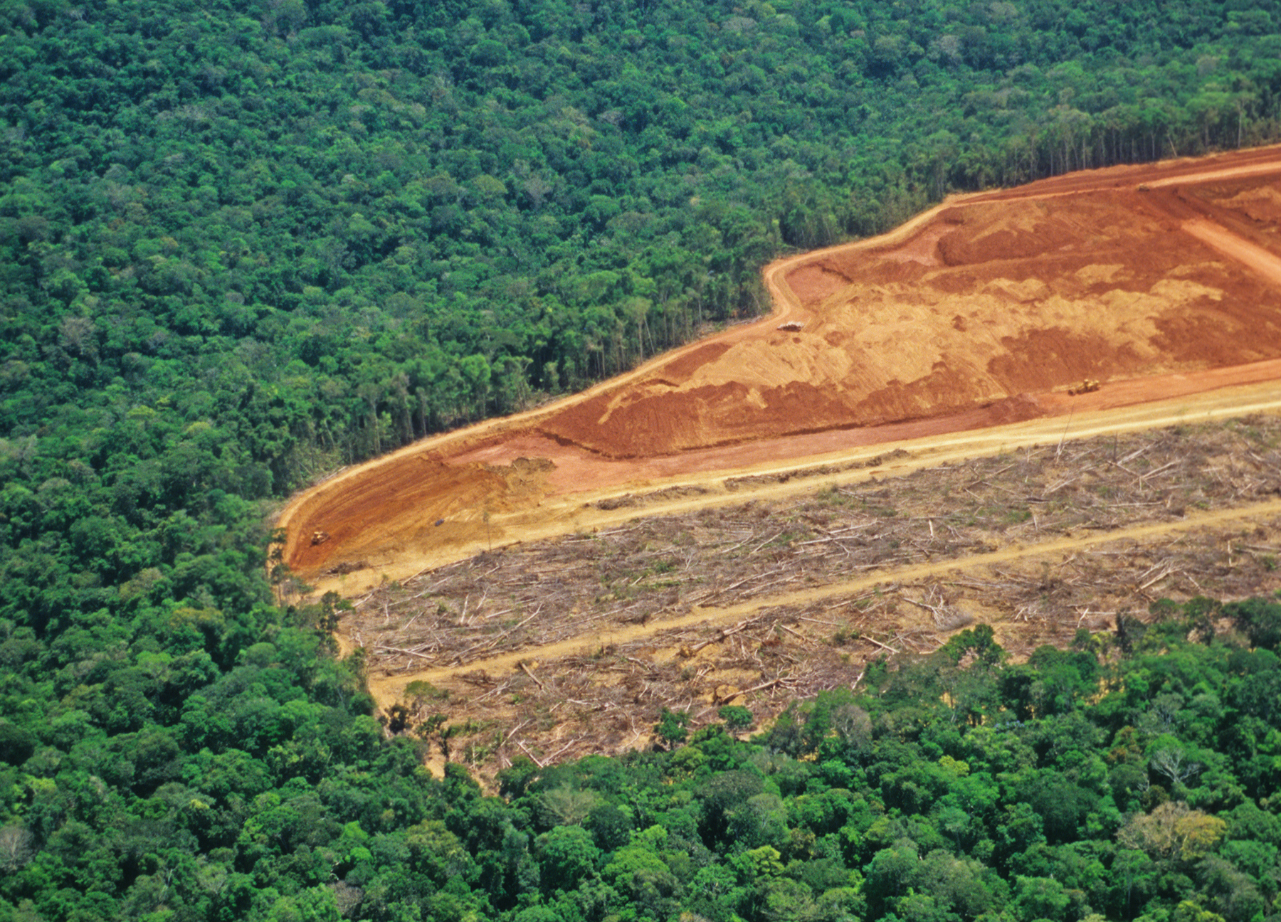 Aerial view showing a large, deforested patch cut into the vast Amazon rainforest