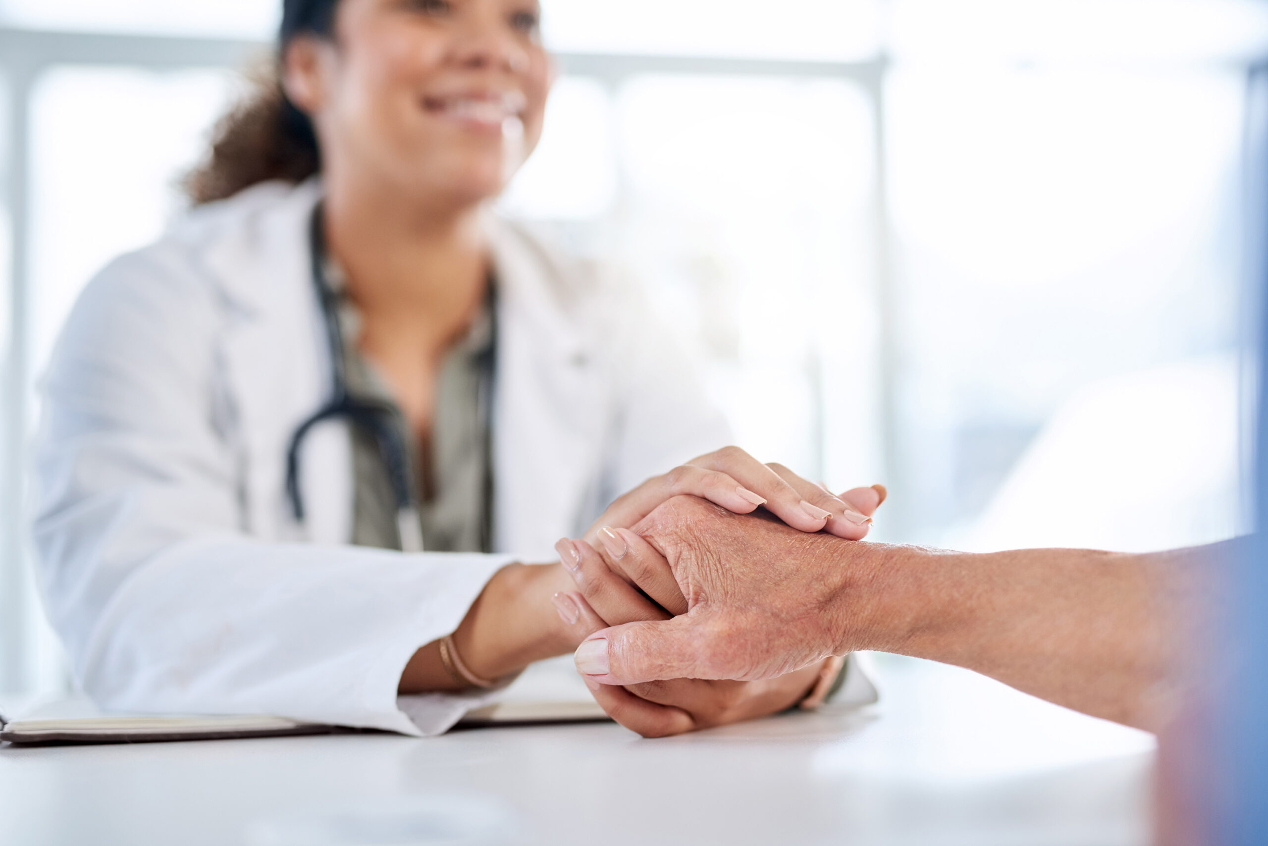 A doctor smiles and holds a patient's hand