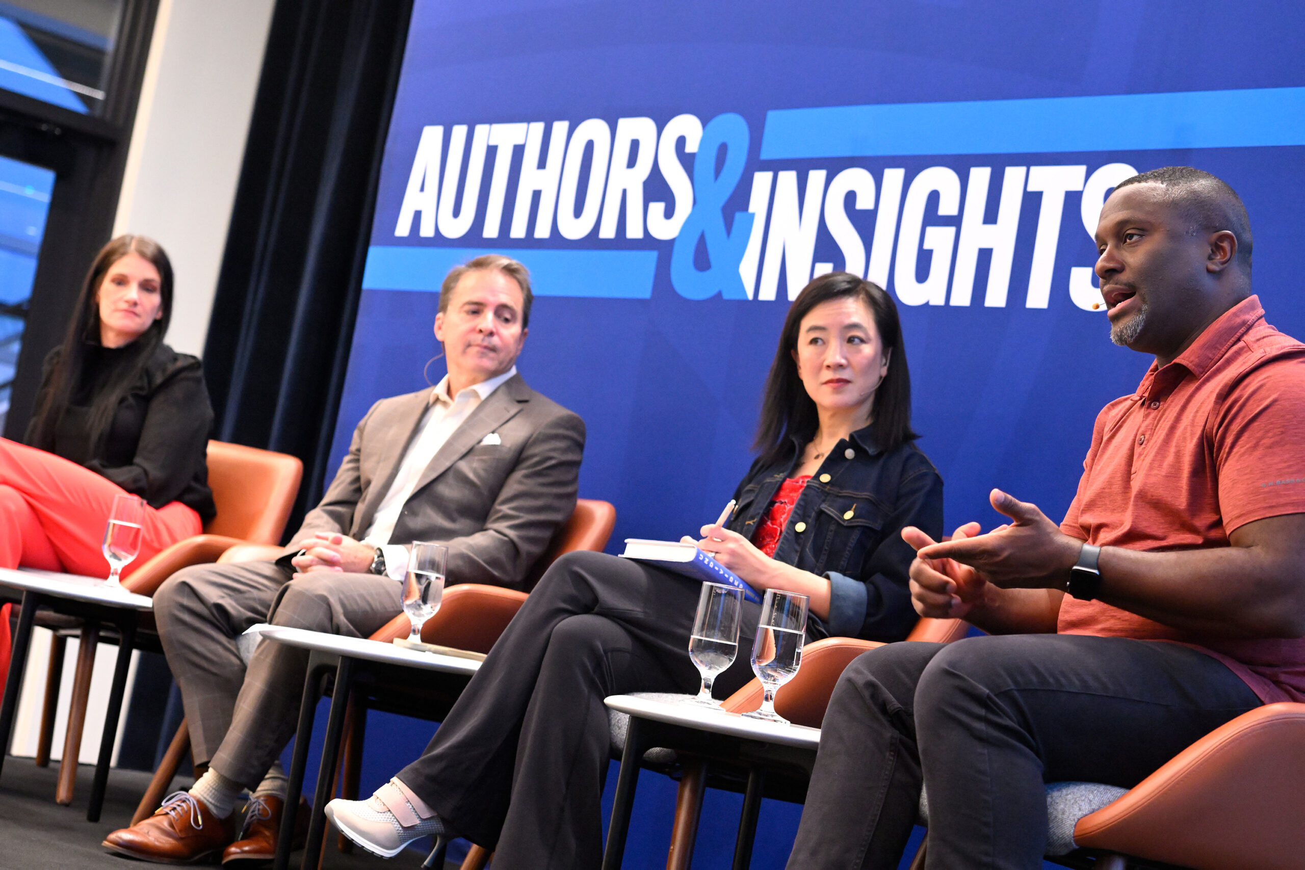 Four panelists converse on stage in front of an Authors & Insights backdrop